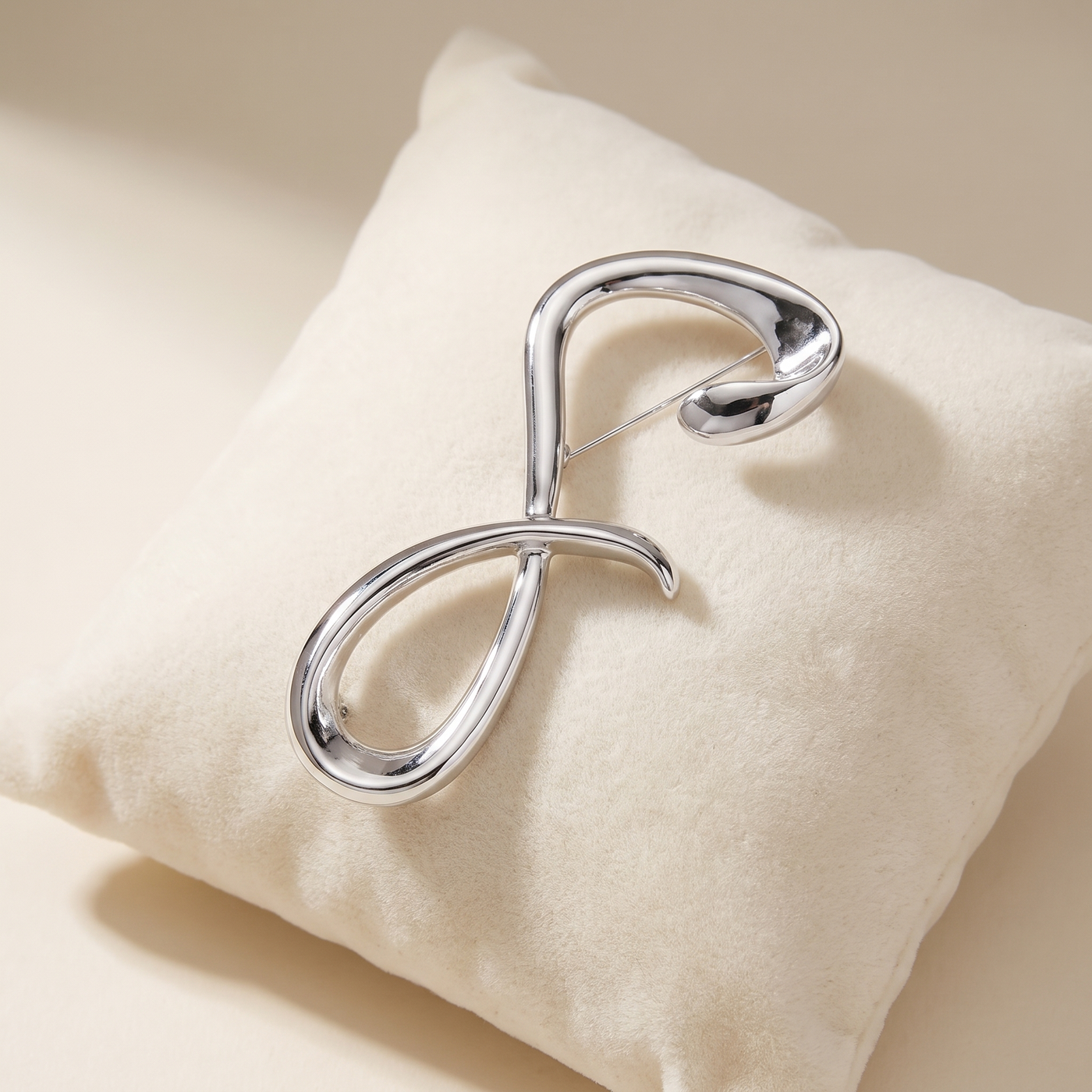 Broche Lettre, bijou fantaisie vintage Alyvoa présentée sur un coussin · Argenté