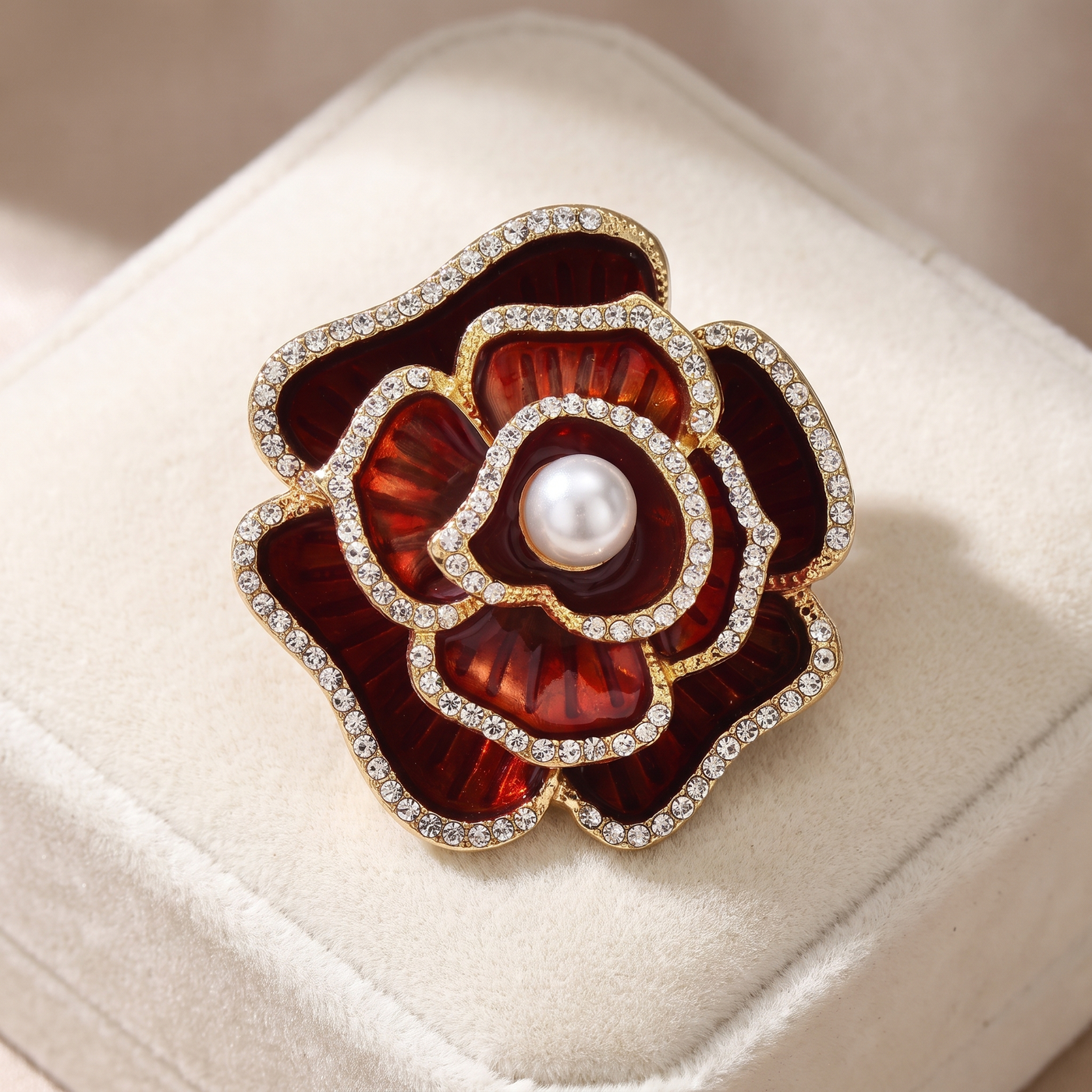 Broche Camélia en émail, bijou vintage Alyvoa présentée sur un coussin · Rouge