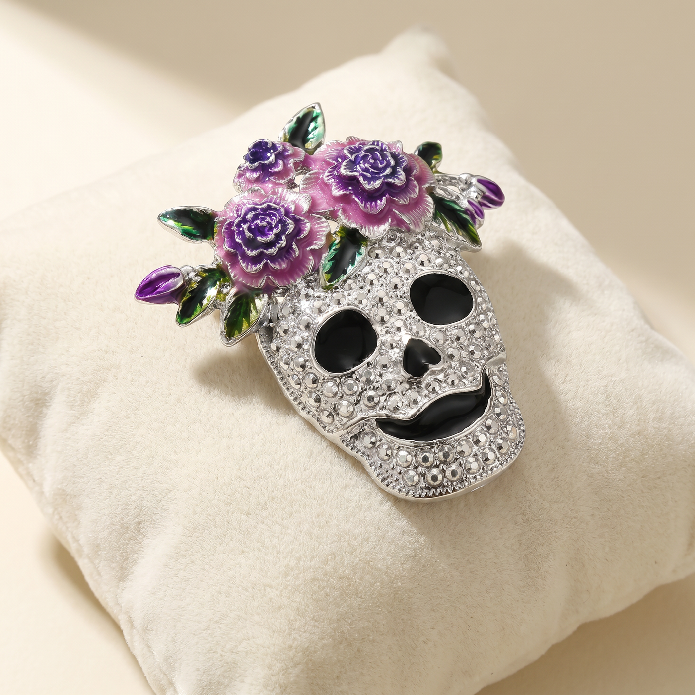 Broche Crâne en émail, bijou vintage Alyvoa présentée sur un coussin